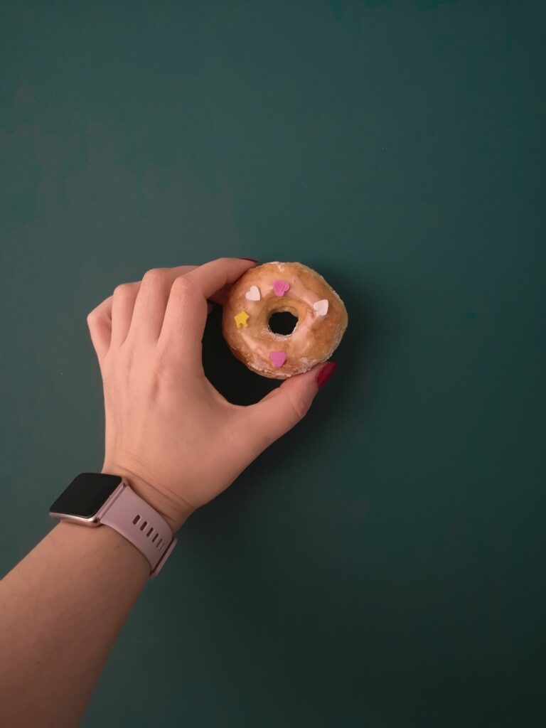 Oponka serowa bez drożdży na tle zielonej ściany. Trzymana przez kobiecą dłoń z różowym smartwatchem Huawei Watch Fit.